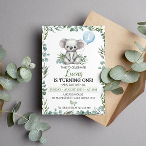 May include: A rectangular invitation card featuring a watercolor koala illustration, a light blue balloon with the number one, and green eucalyptus leaf borders. The text reads: TIME TO CELEBRATE! Lucas IS TURNING ONE! HANG OUT WITH US SUNDAY AUGUST 25TH AT 3PM LUCAS'S HOUSE 123 MAIN STREET, CALIFORNIA. 1235 RSVP TO JENNIFER AT 123.456.789.