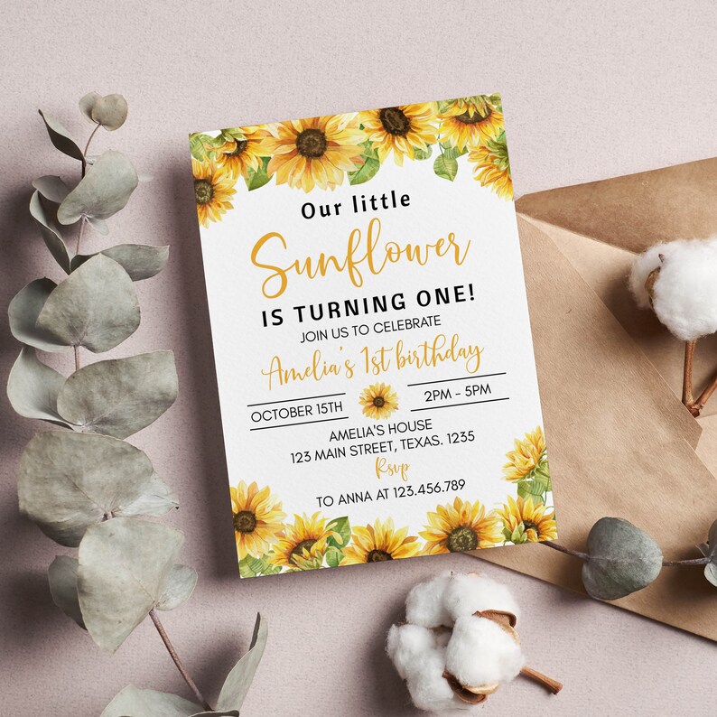 May include: A rectangular birthday invitation card featuring watercolor sunflower illustrations at the top and bottom. The text reads: Our little Sunflower IS TURNING ONE! JOIN US TO CELEBRATE Amelia's 1st birthday OCTOBER 15TH 2PM - 5PM AMELIA'S HOUSE 123 MAIN STREET, TEXAS. 1235 RSVP TO ANNA AT 123.456.789.