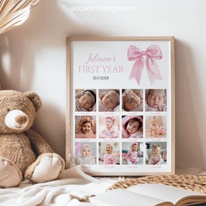 May include: A rectangular framed print titled Juliana's FIRST YEAR with the date 25.11.202X and a large pink bow illustration. The print features a grid of twelve individual photographs documenting a baby's growth from 1 to 12 months.