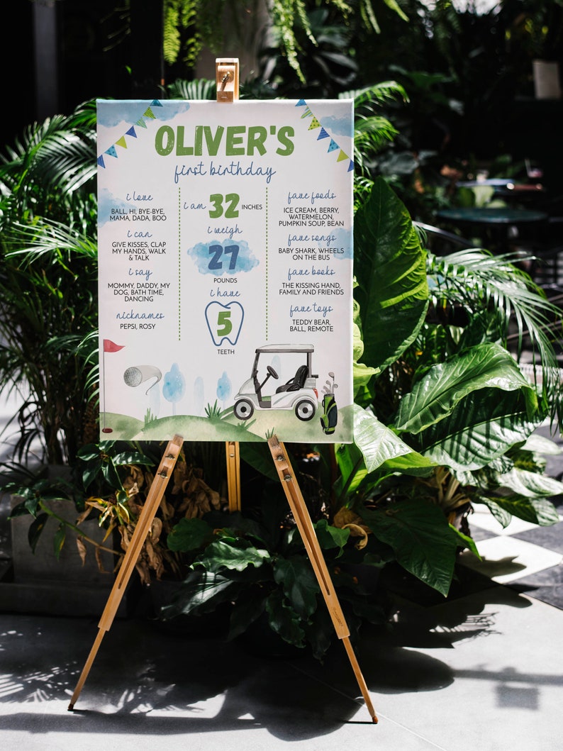 May include: A blue and green illustrated poster with the text "Oliver's first birthday" and details about the child's first year, including height, weight, teeth, and favourite foods, toys, and songs. The poster features a cartoon golf cart.