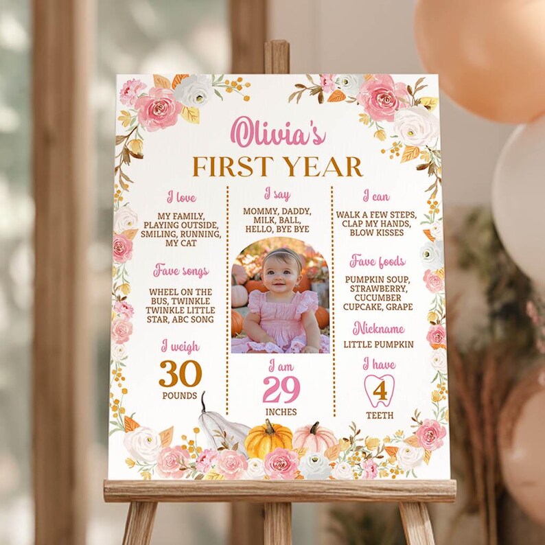 May include: A rectangular milestone sign featuring a floral border with pink and white roses, pumpkins, and text detailing a child's first year. The center displays a photograph of a child, with sections for I love, I say, I can, favorite songs, foods, nickname, weight of 30 pounds, height of 29 inches, and 4 teeth.