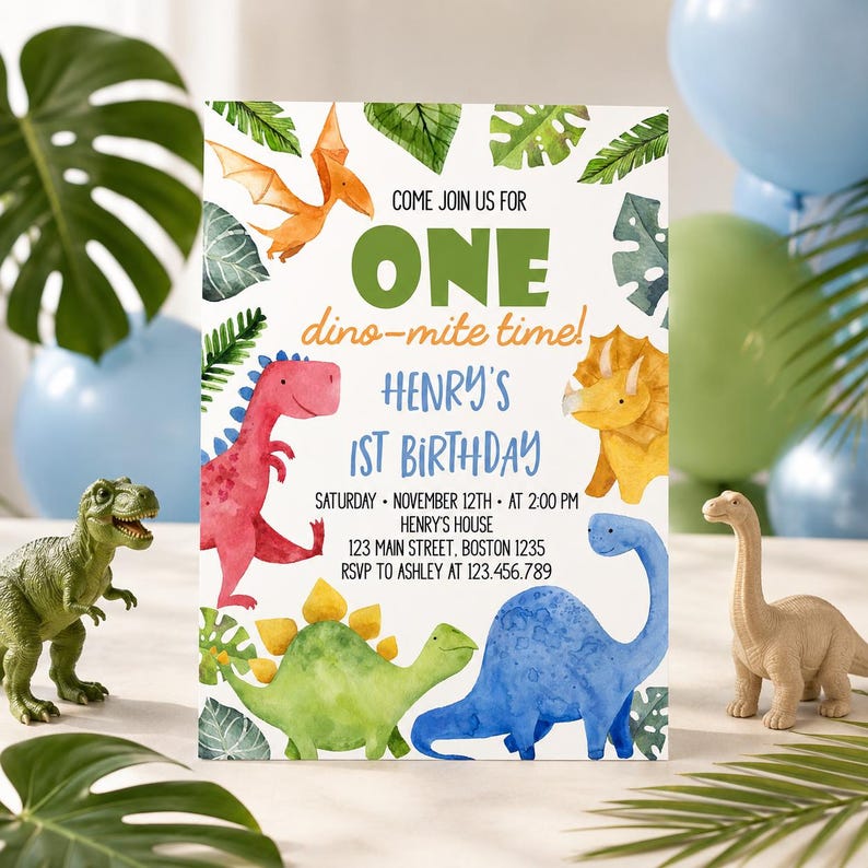 May include: A birthday invitation card featuring watercolor illustrations of various dinosaurs and tropical leaves. The text reads: COME JOIN US FOR ONE dino-mite time! HENRY'S 1ST BIRTHDAY SATURDAY NOVEMBER 12TH AT 2:00 PM HENRY'S HOUSE 123 MAIN STREET BOSTON 1235 RSVP TO ASHLEY AT 123.456.789