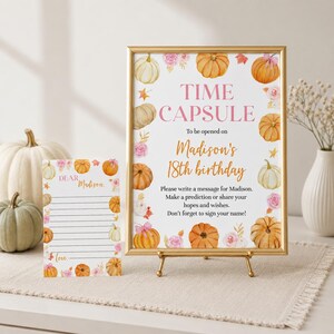 May include: A gold-framed sign and a matching card featuring watercolor pumpkins and pink flowers. The sign reads: TIME CAPSULE To be opened on Madison's 18th birthday. Please write a message for Madison. Make a prediction or share your hopes and wishes.