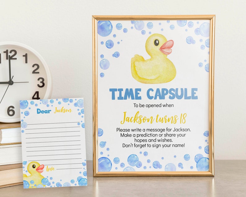 May include: A time capsule sign with a yellow rubber ducky and blue bubbles. The sign says "Time Capsule" and "To be opened when Jackson turns 18". There is a lined sheet of paper with the words "Dear Jackson" and "Love" on it.