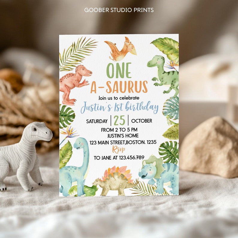Op de afbeelding: Een rechthoekige verjaardagsuitnodigingskaart met aquarelillustraties van verschillende dinosaurussen en tropische bladeren. De tekst luidt ONE A-SAURUS, Justin's 1st birthday, Saturday 25 October, from 2 to 5 PM, Justin's home, 123 Main Street, Boston, 1235, RSVP to Jane at 123.456.789.