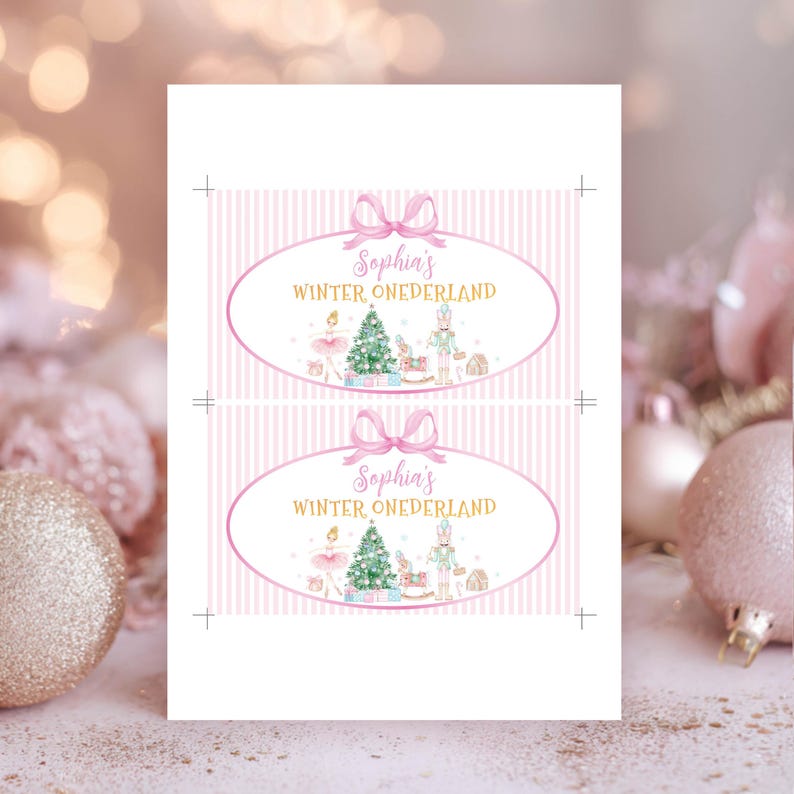 May include: Two rectangular labels with a light pink vertical striped background. Each label features a pink oval frame with a bow, containing the text Sophia's WINTER ONEDERLAND in pink and gold, with illustrations of a ballerina, tree, and nutcracker.