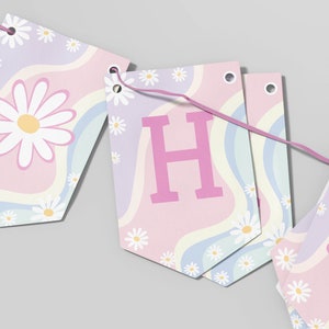 May include: A decorative bunting banner featuring a series of pennants strung on a pink cord. Each pennant displays a pastel wavy pattern in light blue, pink, and lavender, accented with white daisy flowers and a large pink letter H on one piece.