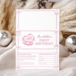May include: A rectangular white card with pink line art borders and bows. It features a pink heart-shaped cake with the word one, the text Charlotte's FIRST BIRTHDAY, and a nutrition facts label listing love, family, friends, fun, and laughter.