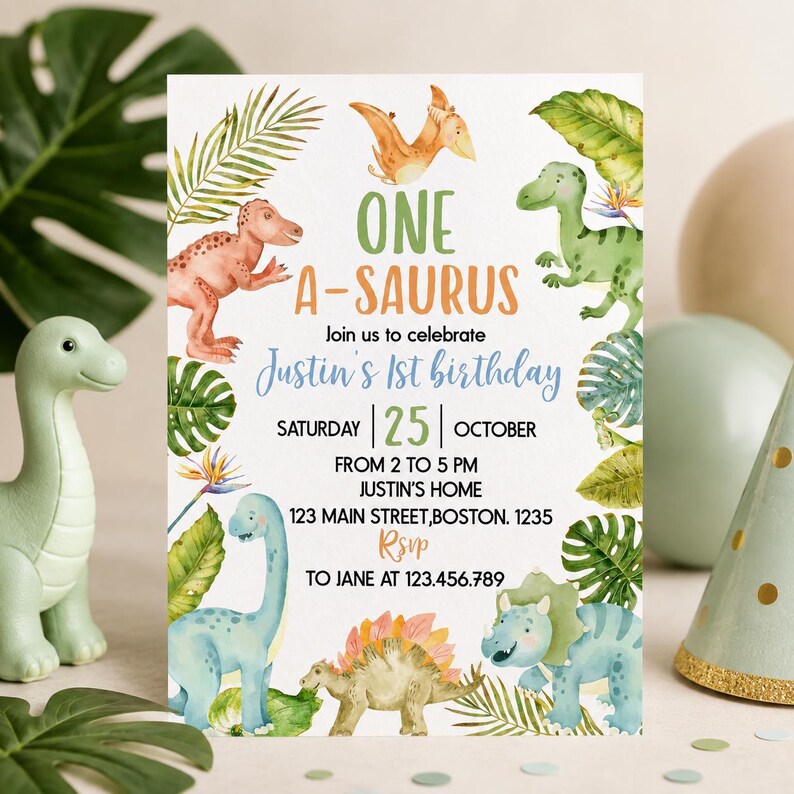 Op de afbeelding: Een rechthoekige verjaardagsuitnodigingskaart met aquarelillustraties van diverse dinosaurussen en tropische bladeren. De tekst luidt: ONE A-SAURUS, Join us to celebrate Justin's 1st birthday, SATURDAY 25 OCTOBER, FROM 2 TO 5 PM, JUSTIN'S HOME, 123 MAIN STREET, BOSTON. 1235, RSVP TO JANE AT 123.456.789.