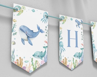 May include: A blue and green ocean-themed banner with the word "Happy" spelled out. Each letter is on a separate flag with a whale, turtle, and jellyfish illustration.