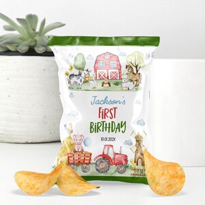May include: A custom snack bag featuring a watercolor farm theme with a red barn, tractor, and various animals. The text reads Jackson's FIRST BIRTHDAY 10.01.202X. The bag is decorated with green borders and is displayed with three potato chips in the foreground.