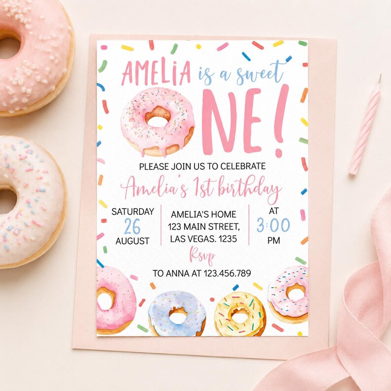 May include: A rectangular birthday invitation card featuring a watercolor donut theme with colorful sprinkles. The text reads: AMELIA is a sweet ONE! PLEASE JOIN US TO CELEBRATE Amelia's 1st birthday, Saturday 26 August, 3:00 PM, RSVP to 123.456.789.