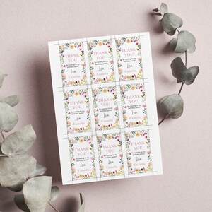 May include: A sheet of nine rectangular paper tags featuring a floral border with pink, yellow, and blue flowers. Each tag displays the text "THANK YOU for coming to my birthday party! Love, Camelia" in pink and black lettering on a white background.