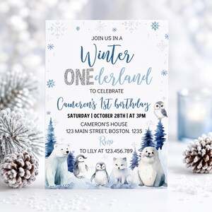 May include: A rectangular invitation card featuring the text JOIN US IN A Winter ONEderland TO CELEBRATE Cameron's 1st birthday. The design includes blue and silver snowflakes, watercolor illustrations of a polar bear, penguins, a fox, and a seal.