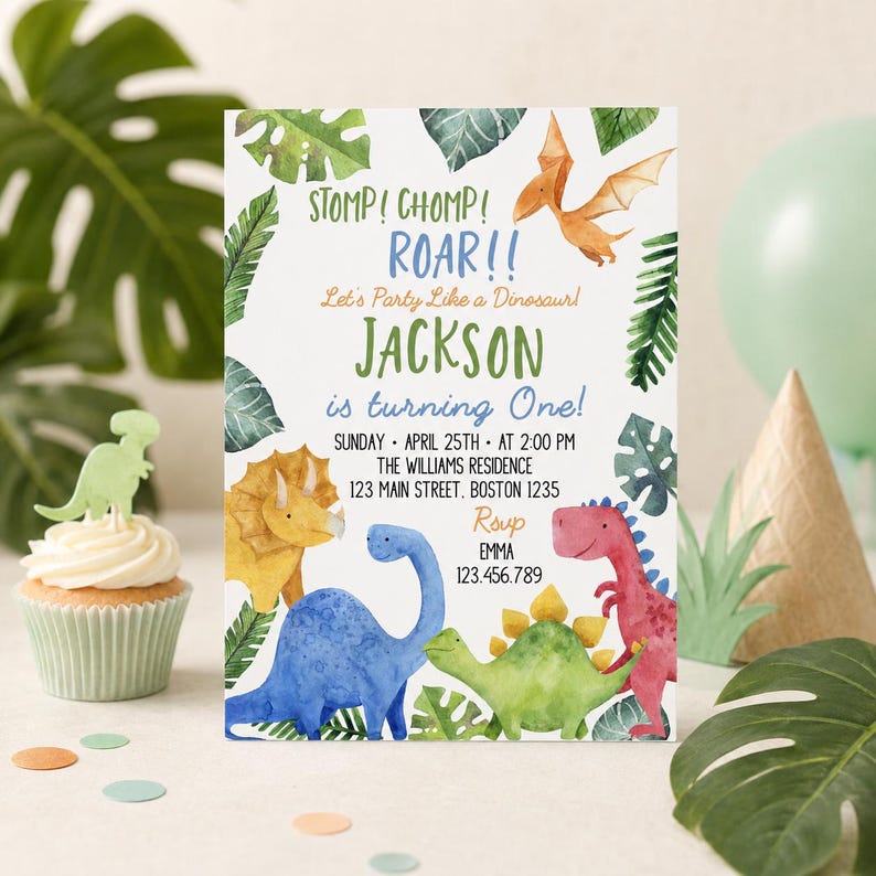 May include: A rectangular birthday invitation card featuring watercolor illustrations of various dinosaurs and tropical leaves. The text reads: STOMP! CHOMP! ROAR!! Let's Party Like a Dinosaur! JACKSON is turning One! SUNDAY APRIL 25TH AT 2:00 PM THE WILLIAMS RESIDENCE 123 MAIN STREET. BOSTON 1235 RSVP EMMA 123.456.789.