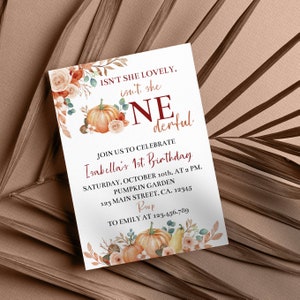 May include: A rectangular birthday invitation card featuring watercolour illustrations of orange pumpkins, beige roses, and autumn leaves. The text reads: ISN'T SHE LOVELY, isn't she ONEderful, JOIN US TO CELEBRATE Isabella's 1st Birthday, SATURDAY, OCTOBER 10th, AT 2 PM.