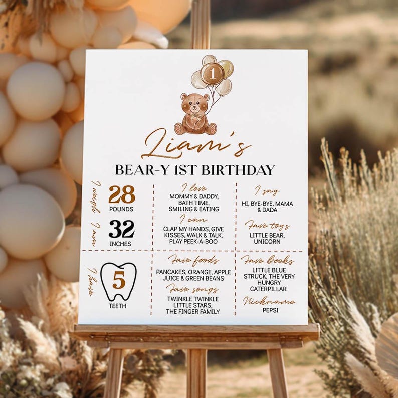 Puede incluir: Un cartel de cumplea&ntilde;os blanco para el primer aniversario de Liam con una ilustraci&oacute;n de un oso pardo y globos, que enumera 12,7 kg, 81,3 cm, 5 dientes, comidas, libros, canciones, juguetes y hitos favoritos en texto marr&oacute;n y negro.