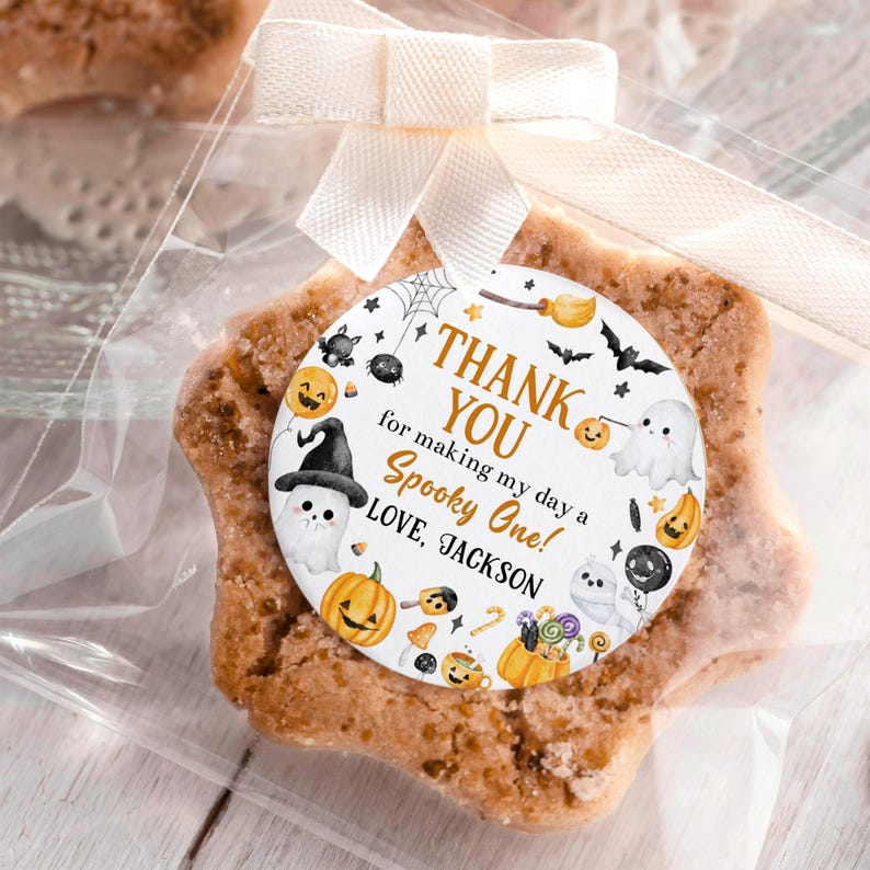 May include: A star-shaped cookie in a clear cellophane bag, tied with a white ribbon. A round tag with Halloween-themed illustrations and the text "THANK YOU for making my day a Spooky One! LOVE, JACKSON" is attached.