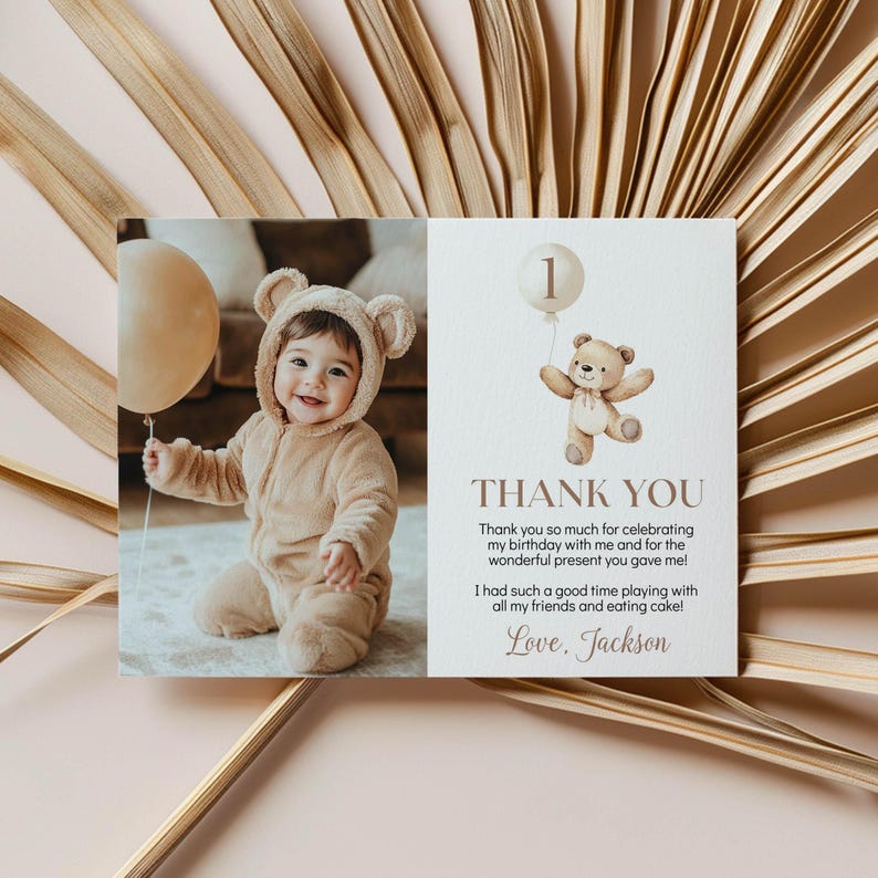 May include: A rectangular thank you card featuring a photo of a baby in a tan bear-ear onesie holding a beige balloon on the left. The right side shows a watercolor teddy bear with a balloon, the number 1, and text reading Thank You, Jackson.