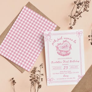 May include: A pink and white gingham patterned invitation card with a pink and white illustration of a heart-shaped cake with the text "girls just wanna be one" and the text "Join us to celebrate Charlotte's First Birthday" with the date and time of the party.