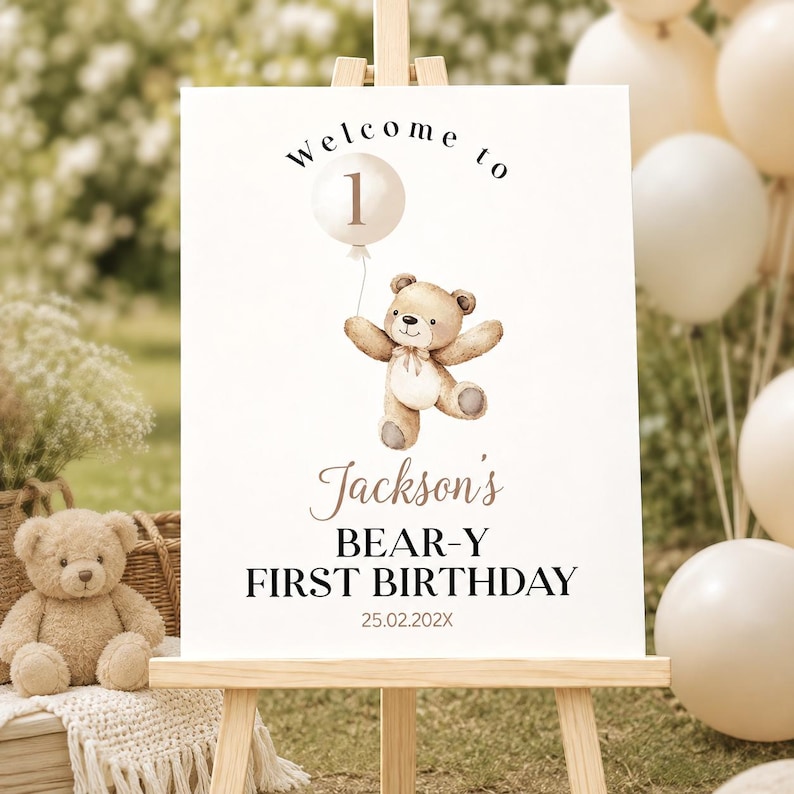 May include: A white rectangular sign on a wooden easel featuring a watercolor illustration of a brown teddy bear holding a balloon with the number 1. The text reads Welcome to Jackson's BEAR-Y FIRST BIRTHDAY and the date 25.02.202X in black.