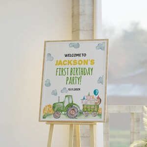 K&ouml;nnte beinhalten: Ein rechteckiges Geburtstagsschild in einem Holzrahmen mit einem gr&uuml;nen Traktor, der einen Wagen mit Tieren in Partyh&uuml;ten zieht, blauen Wolken und dem Text: WELCOME TO JACKSON'S FIRST BIRTHDAY PARTY! 15.11.202X. Das Design ist in Aquarelloptik.