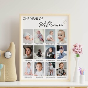 May include: A vertical rectangular poster in a light wood frame titled ONE YEAR OF William with a small heart icon. It features a grid of twelve individual photographs documenting a child's growth from one month to twelve months of age.