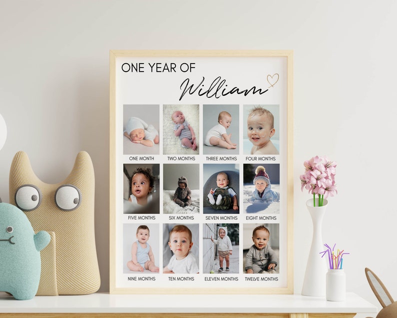 May include: A vertical rectangular poster in a light wood frame titled ONE YEAR OF William with a small heart icon. It features a grid of twelve individual photographs documenting a child's growth from one month to twelve months of age.