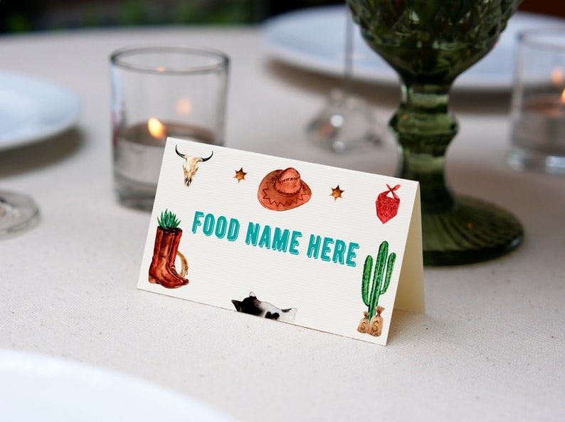 K&ouml;nnte beinhalten: Eine gefaltete wei&szlig;e Karte mit dem Text FOOD NAME HERE in T&uuml;rkis. Die Karte zeigt Aquarellillustrationen eines Kuhsch&auml;dels, eines braunen Cowboyhuts, eines roten Bandanas, eines braunen Stiefels mit Sukkulente, eines gr&uuml;nen Kaktus und einer schwarz-wei&szlig;en Katze.