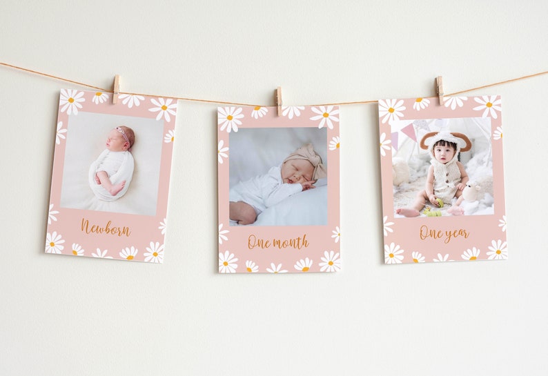 Puede incluir: Tres tarjetas de fotos rosas con patrones de margaritas blancas y texto dorado. Las tarjetas est&aacute;n colgadas de una cuerda con pinzas para la ropa. Cada tarjeta presenta un beb&eacute; a diferentes edades: reci&eacute;n nacido, un mes y un a&ntilde;o. El texto en las tarjetas dice "Reci&eacute;n nacido", "Un mes" y "Un a&ntilde;o".