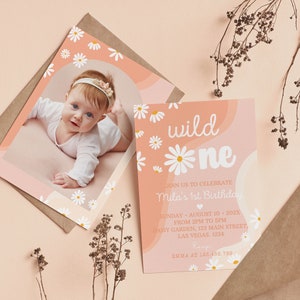 May include: A birthday invitation card featuring a photo of a baby and the text "wild one" with white daisy illustrations on a peach background. The card includes event details for Mila's 1st birthday on August 10, 202X, at Daisy Garden.