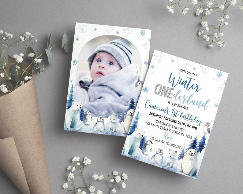 May include: A rectangular invitation card featuring a winter theme with blue snowflakes, a polar bear, penguins, an owl, and a seal. The text reads: JOIN US IN A Winter ONEderland TO CELEBRATE Cameron's 1st birthday SATURDAY | OCTOBER 28TH | AT 3PM.