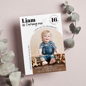 May include: A rectangular birthday invitation card featuring a photo of a child in blue denim overalls and a striped shirt sitting with wooden toy airplanes. The text reads Liam is turning one, Saturday December 16, 202X, and event details.