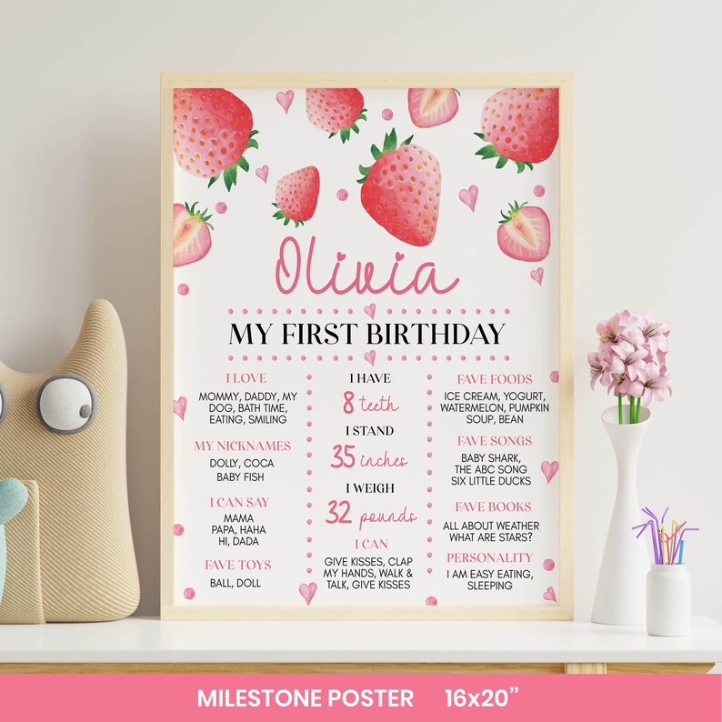 Pode incluir: Um cartaz de marcos em uma moldura de madeira clara com tema de morango, cora&ccedil;&otilde;es e pontos rosa. O texto diz Olivia My First Birthday, listando detalhes pessoais incluindo 8 dentes, 35 polegadas e 32 libras, com comidas, m&uacute;sicas e brinquedos favoritos.