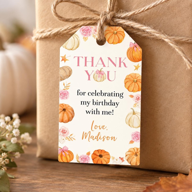 May include: A rectangular gift tag with a white background featuring watercolor illustrations of orange and white pumpkins and pink roses. The text reads: THANK YOU for celebrating my birthday with me! Love, Madison. The tag is tied with brown twine.