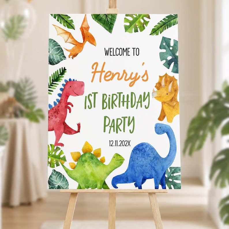 Op de afbeelding: Een wit rechthoekig verjaardagsbord met aquarelillustraties van een rode, gele, groene en blauwe dinosaurus en een oranje pterosauri&euml;r. De tekst luidt: WELCOME TO Henry's 1ST BIRTHDAY PARTY 12.11.202X, omringd door groene tropische bladeren.