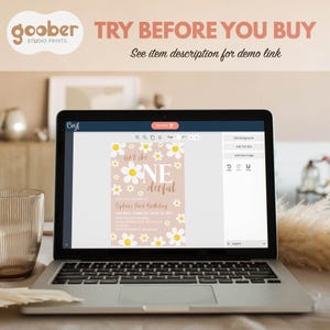 May include: A laptop screen displaying a digital birthday invitation template with a light pink background, white daisy flowers, and the text "isn't she ONEderful". The interface includes editing tools, a "BUY NOW" button, and the text "TRY BEFORE YOU BUY".