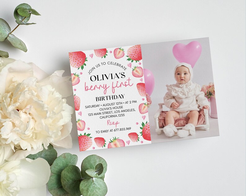 May include: A rectangular birthday invitation card featuring a watercolor strawberry border and text that reads JOIN US TO CELEBRATE OLIVIA'S berry first BIRTHDAY SATURDAY AUGUST 12TH AT 2 PM OLIVIA'S HOUSE 123 MAIN STREET LOS ANGELES CALIFORNIA 1235 RSVP TO EMILY AT 677.855.969.