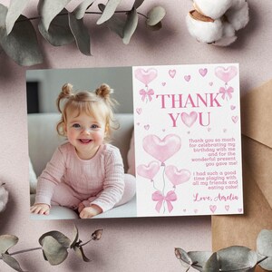 May include: Pink thank you card with a photo of a young girl and a message thanking guests for celebrating her birthday. The card features pink hearts and the text "Thank You" in pink.