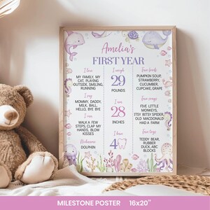 May include: A rectangular milestone poster titled Amelia's FIRST YEAR with purple text and watercolor sea creature illustrations including a dolphin, whale, and octopus. It lists personal details like 29 pounds and 28 inches in a grid format.