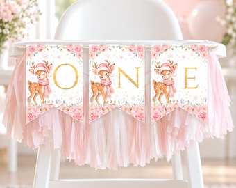 May include: A high chair banner featuring three pennants with pink floral borders and a fawn wearing a pink hat and scarf. Each pennant displays a large gold letter spelling out the word ONE, accented with gold dots on a white background.
