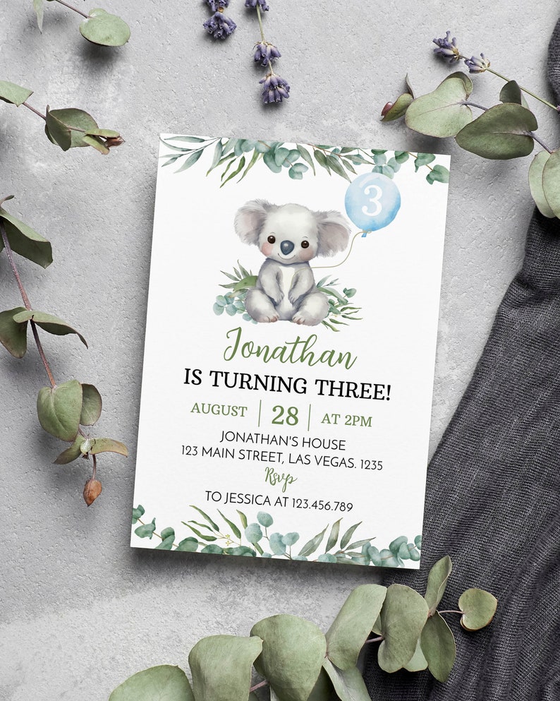 May include: A rectangular birthday invitation card featuring a watercolor illustration of a koala holding a light blue balloon with the number 3. The text reads: Jonathan IS TURNING THREE! AUGUST 28 AT 2PM JONATHAN'S HOUSE 123 MAIN STREET, LAS VEGAS. 1235 RSVP TO JESSICA AT 123.456.789.