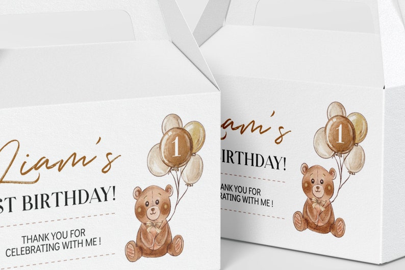 May include: Two white cardboard gable boxes featuring a watercolour illustration of a brown teddy bear holding a cluster of balloons with the number one on the centre balloon. The text reads Liam's 1st BIRTHDAY! THANK YOU FOR CELEBRATING WITH ME!