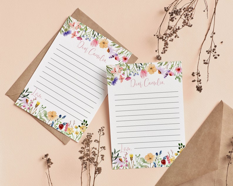 May include: Two white stationery sheets with horizontal black lines, featuring watercolor floral borders in pink, yellow, blue, and green. The text "Dear Camelia" is printed at the top, and the word "Love" is printed at the bottom of each sheet.