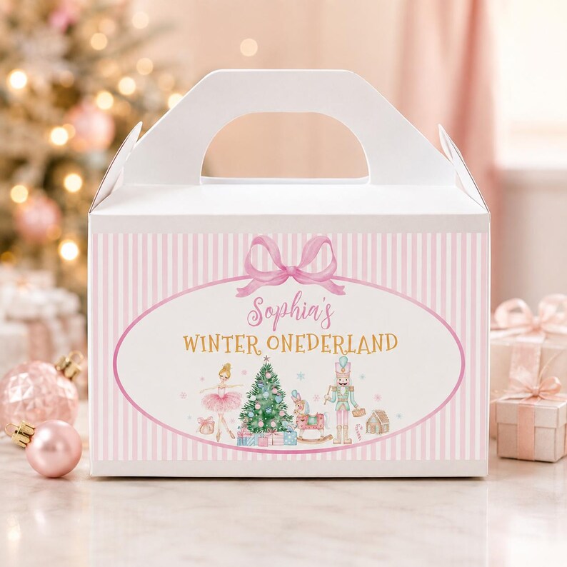 May include: A white gable box with a light pink vertical striped pattern. The front features an oval frame with a pink bow, the text "Sophia's WINTER ONEDERLAND," and illustrations of a ballerina, a Christmas tree, a nutcracker, and gifts.
