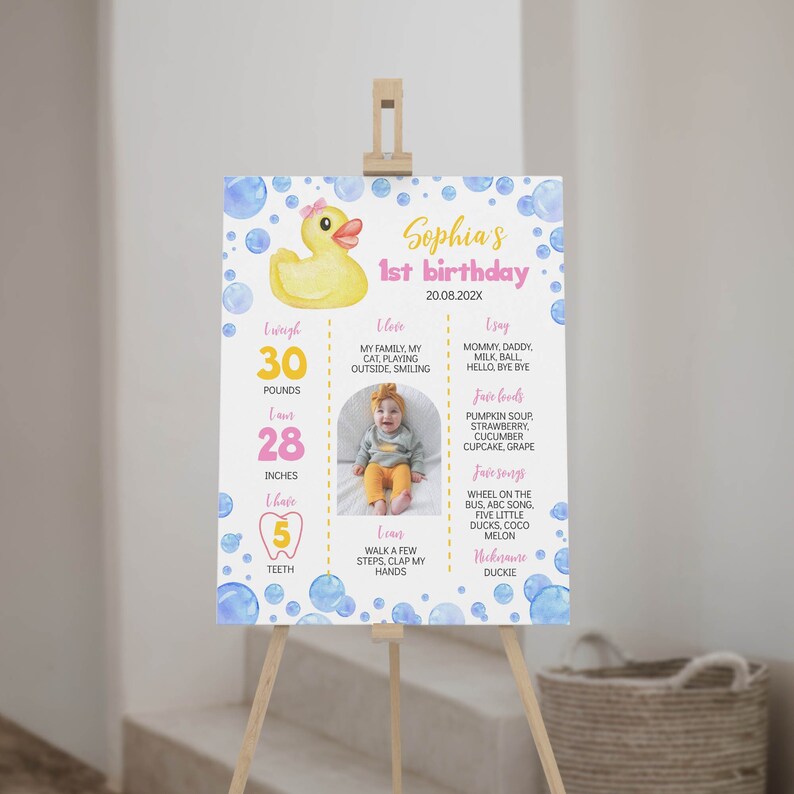 May include: A birthday milestone sign featuring a yellow rubber duck with a pink bow, blue watercolor bubbles, and text including Sophia's 1st birthday, 20.08.202X, weight 30 pounds, 28 inches, 5 teeth, and various personal facts with a central photo.