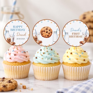 May include: Three cupcakes with pink, light blue, and yellow frosting, each topped with a circular paper topper. The toppers feature illustrations of milk bottles, chocolate chip cookies, and text including Happy Birthday, Daniel, and First Birthday.