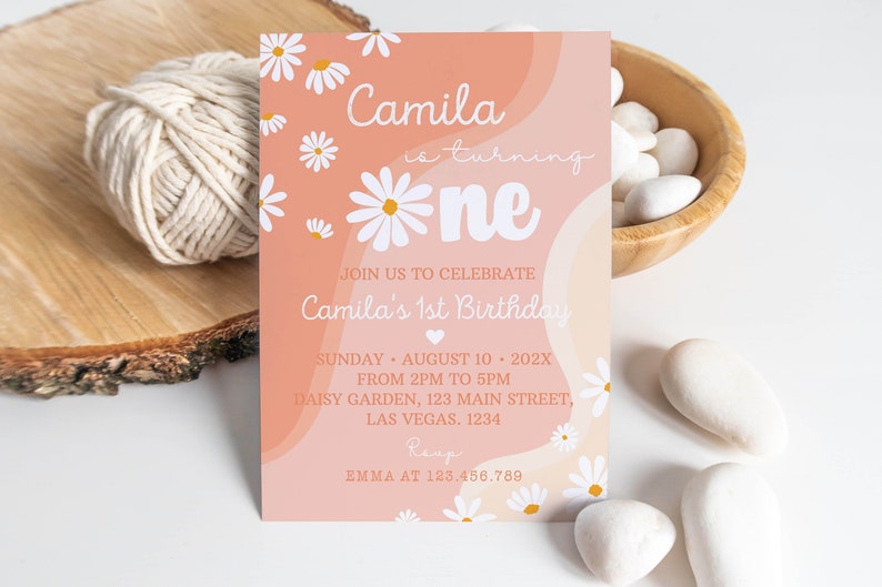 Peut inclure: Une carte d'invitation d'anniversaire rectangulaire avec un fond ondul&eacute; p&ecirc;che et cr&egrave;me et des illustrations de marguerites blanches. Le texte indique : Camila is turning one, Join us to celebrate Camila's 1st Birthday, Sunday August 10 202X, 2pm to 5pm, Daisy Garden, 123 Main Street, Las Vegas 1234, RSVP Emma at 123.456.789.