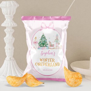May include: A snack bag with a pink and white striped design featuring a central oval graphic of a Christmas tree, a ballerina, a nutcracker, and a rocking horse. The text reads Sophia's WINTER ONEDERLAND and the date 16.12.202X.