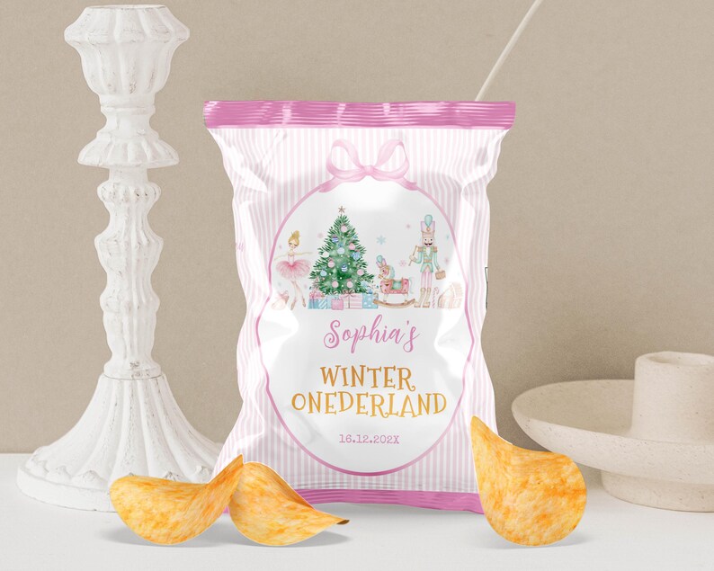 May include: A snack bag with a pink and white striped design featuring a central oval graphic of a Christmas tree, a ballerina, a nutcracker, and a rocking horse. The text reads Sophia's WINTER ONEDERLAND and the date 16.12.202X.
